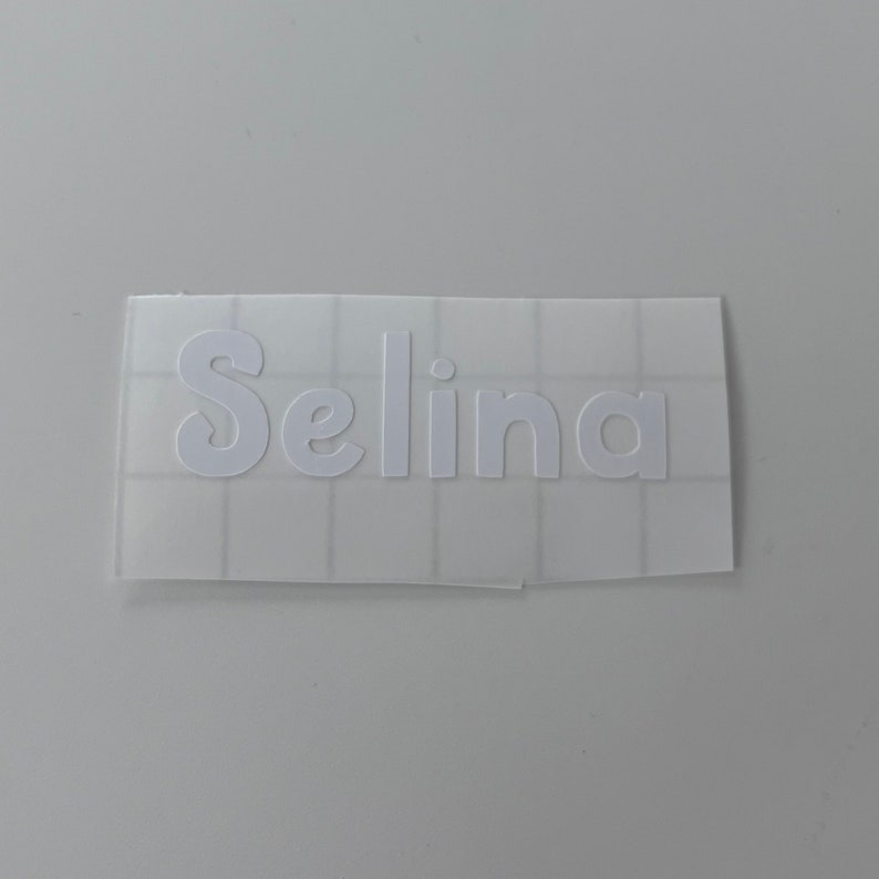 May include: White vinyl sticker with the name "Selina" in a cursive font.