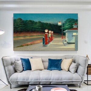 Op de afbeelding: Een schilderij van een tankstation 's nachts met drie rode benzinepompen en een wit gebouw. Het tankstation bevindt zich in een landelijke omgeving met bomen op de achtergrond. Het schilderij is in realistische stijl en heeft een gedempt kleurenpalet.