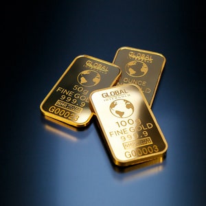 Puede incluir: Tres barras de oro con las palabras "GLOBAL INTERGOLD" y "FINE GOLD" impresas en ellas. Las barras están etiquetadas con diferentes pesos: 50g, 100g y 1 onza.