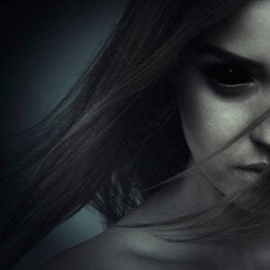 Puede incluir: Primer plano de la cara de una mujer con cabello oscuro que cubre la mayor parte de su rostro. Sus ojos son negros y su expresión es seria.