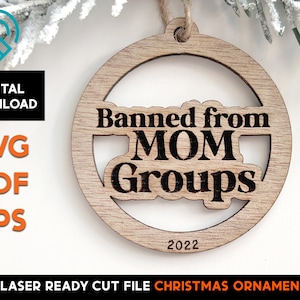 May include: A round wooden Christmas ornament with the text "Banned from MOM Groups" and the year "2022" engraved on it.