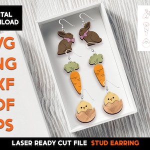 Pode incluir: Um conjunto de brincos de botão de madeira cortados a laser com temas de Páscoa. Os brincos incluem um coelho, uma cenoura e um pintinho em um ovo. Os brincos são exibidos em uma caixa branca com o texto "Laser Ready Cut File Stud Earring" na parte inferior.