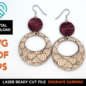 May include: A pair of laser cut wood earrings with a pumpkin pattern. The earrings are made of two pieces, a round disc with a pumpkin pattern and a smaller round disc with a wood grain finish. The earrings are attached to silver ear wires.