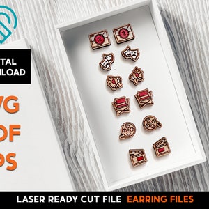 May include: A white box with a variety of laser cut wooden earrings. The earrings are in the shape of film reels, clapperboards, director's chairs, and other movie-themed designs. The earrings are all red and brown.