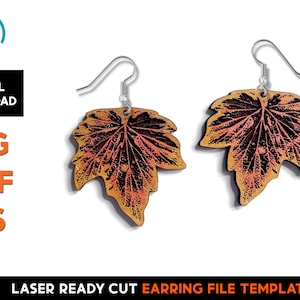 May include: A pair of laser cut earrings featuring a detailed maple leaf design. The leaves are a gradient of orange and brown, with a silver hook.