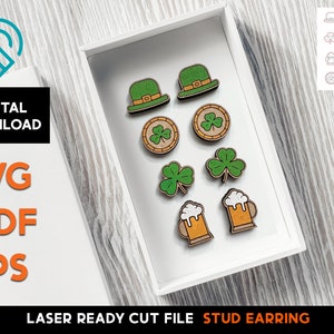 Op de afbeelding: Een verzameling lasergesneden houten oorstekers in een witte doos. De oorbellen hebben St. Patrick's Day-ontwerpen, waaronder groene hoeden, klavers en bierpullen. De afbeelding bevat ook de tekst "DIGITAL DOWNLOAD" en "SVG PDF EPS".