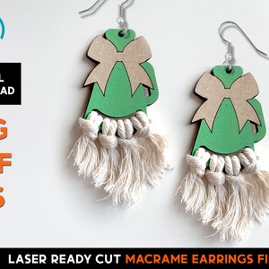 Puede incluir: Un par de pendientes de madera verde y marrón con un lazo y un borla de macramé. Los pendientes están cortados con láser y listos para ensamblar.