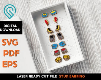 May include: A white box with a variety of colorful stud earrings. The earrings are shaped like retro video game consoles, roller skates, phones, and floppy disks. The box is sitting on a light wood surface.  Laser Ready Cut File Stud Earring.