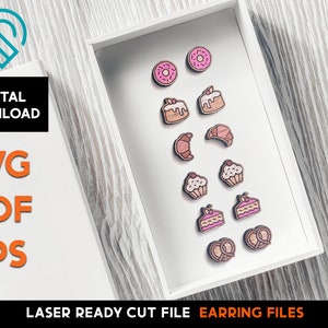 Puede incluir: Una caja blanca con una variedad de pendientes de madera en forma de rosquillas, pasteles, bollería y pretzels. Los pendientes están cortados con láser y listos para ensamblar. El texto "LASER READY CUT FILE EARRING FILES" está impreso debajo de la caja.