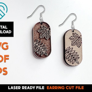 Puede incluir: Un par de pendientes de madera cortados con láser con un diseño de hojas. Los pendientes son marrones y tienen un gancho plateado.