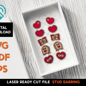 May include: A white box contains laser-cut wooden stud earrings with red heart and tombstone designs. The earrings have a distressed look, some with band-aids. The image also includes the text "DIGITAL DOWNLOAD" and "LASER READY CUT FILE STUD EARRING".