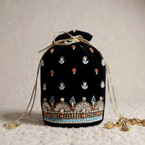 Könnte beinhalten: Schwarzer Samtbeutel mit Kordelzug und Perlenverzierungen. Der Beutel ist mit kleinen, farbigen Perlen und einem detaillierten Rand mit Perlen und türkisfarbenen Akzenten verziert. Ein dekoratives Accessoire.