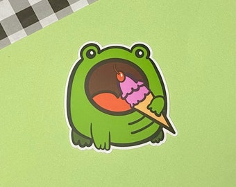 May include: A green frog sticker with a wide open mouth eating a pink and brown ice cream cone.