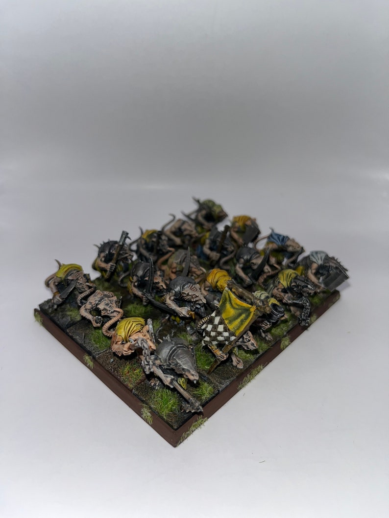 Peut inclure: Un groupe de 18 figurines miniatures peintes de cr&eacute;atures ressemblant &agrave; des rats avec des &eacute;p&eacute;es et des boucliers, debout sur une base brune avec de l'herbe verte. Les figurines sont peintes dans des tons de gris, de brun et de jaune.