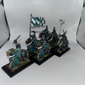 Peut inclure: Un groupe de six chevaliers miniatures &agrave; cheval, peints en vert et blanc, avec des &eacute;p&eacute;es et des boucliers. Les chevaliers sont dispos&eacute;s en ligne, avec un drapeau &agrave; l'avant.
