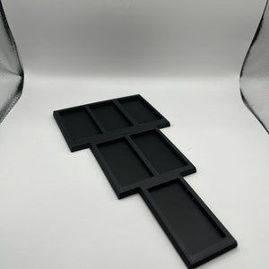 Peut inclure: Plateau en plastique noir avec plusieurs compartiments, con&ccedil;u pour organiser de petits objets.