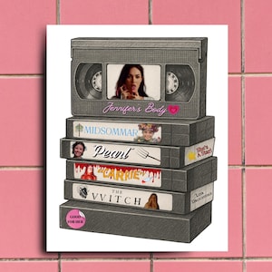 Puede incluir: Una pila de cintas VHS grises con títulos de películas como "Jennifer's Body", "Midsommar" y "Pearl". Las cintas están apiladas una encima de otra, con la cinta superior que muestra una imagen de la película y el título. El fondo es una pared de azulejos rosas.