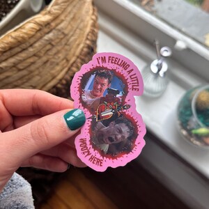 May include: Pink sticker with a bloody splatter design. The sticker features two images of a man with the text "I'm feeling a little woozy here".