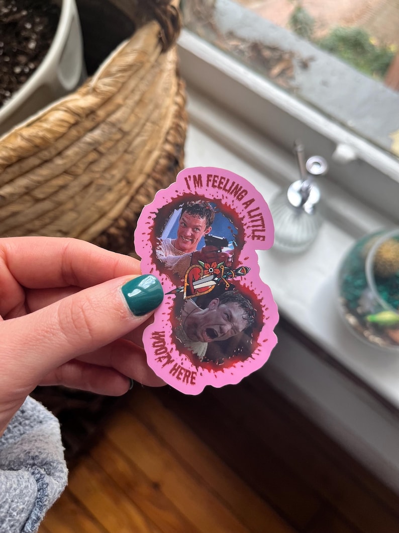 May include: Pink sticker with a bloody splatter design. The sticker features two images of a man with the text "I'm feeling a little woozy here".