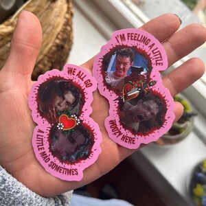 May include: Two pink heart-shaped stickers with bloody edges. The stickers feature characters from the movie "American Psycho". The text on the stickers reads "I'm feeling a little kooky here" and "We all go a little mad sometimes".