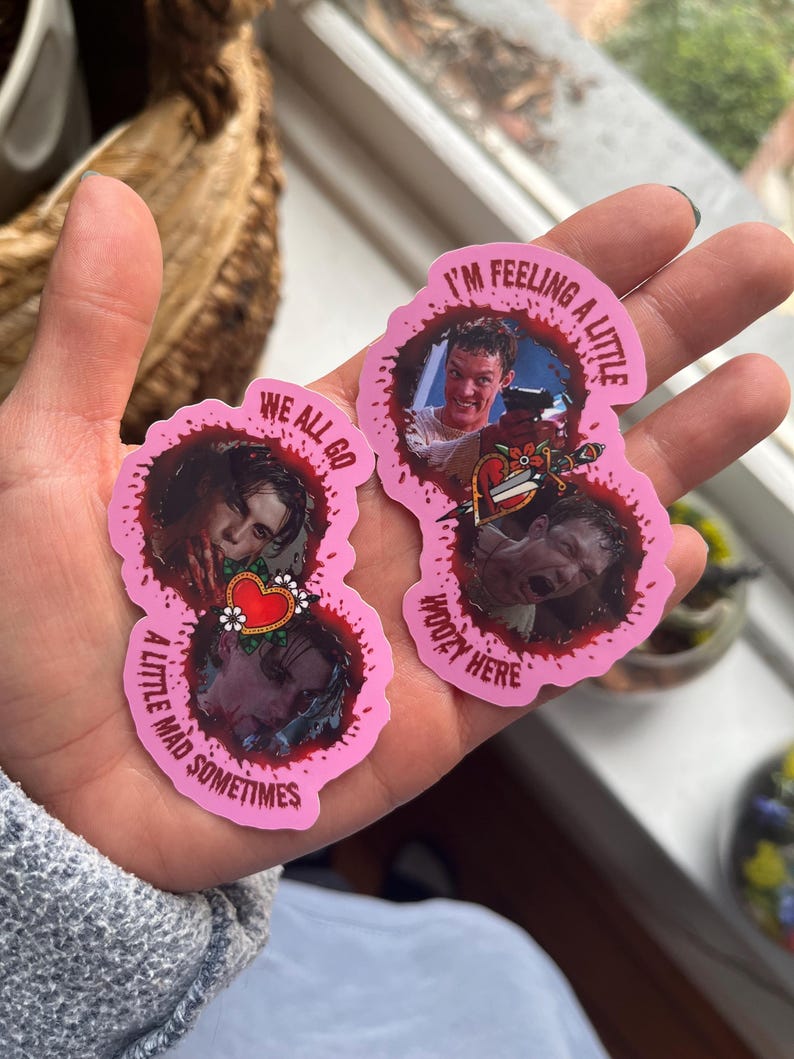 May include: Two pink heart-shaped stickers with bloody edges. The stickers feature characters from the movie "American Psycho". The text on the stickers reads "I'm feeling a little kooky here" and "We all go a little mad sometimes".