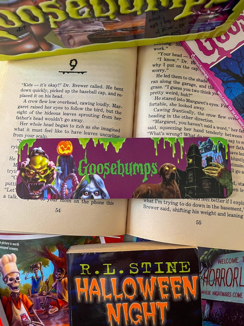May include: A purple Goosebumps book with a green, slimy monster on the cover. The book is open to page 54 and the text reads "Kids - it's okay!" Dr. Brewer called. He bent down quickly, picked up the baseball cap, and replaced it on his head."