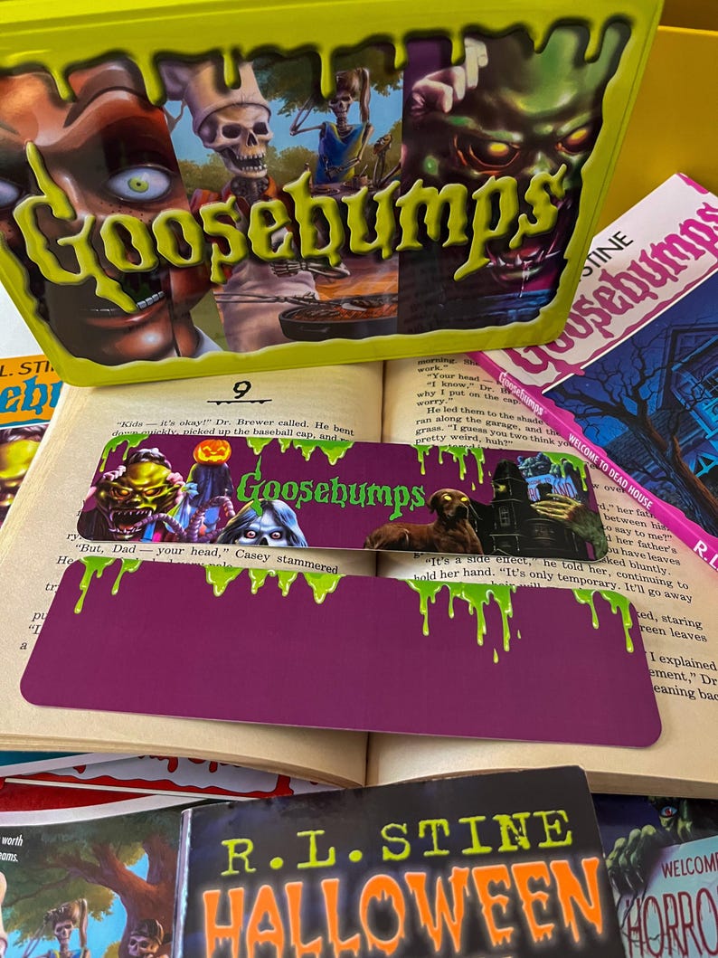 May include: A stack of Goosebumps books with a green, purple, and pink bookmark. The bookmark features a monster with green slime dripping from its head. The text on the bookmark reads "Goosebumps".