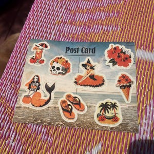May include: A rectangular postcard featuring a collage of Halloween-themed illustrations over a beach scene. Images include a cocktail, a skull with flowers, a witch, hibiscus flowers, a skeleton mermaid, flip-flops, an ice cream cone, and palm trees.