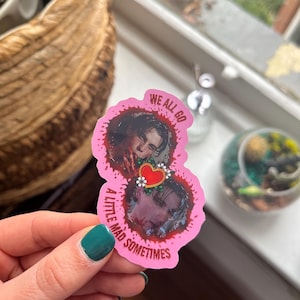 May include: Pink sticker with two images of a person with blood splatters around them. The text on the sticker reads "We all go a little mad sometimes".