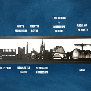 May include: Black and white silhouette of the Newcastle skyline, including St. James' Park, Newcastle Castle, Newcastle Cathedral, Tyne Bridge & Millennium Bridge, and the Angel of the North.