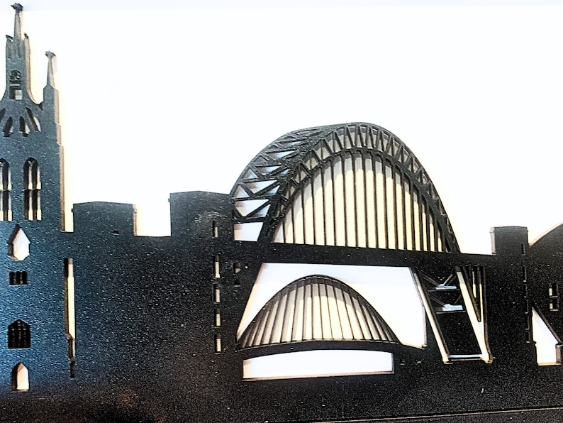 May include: Black silhouette of a city skyline with a tall church building on the left and a large arch bridge in the center.