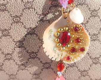 Llavero artesanal elaborado con conchas marinas naturales, una pieza única y elegante, adornada con perlas y colores delicados, que evoca un ambiente de vacaciones junto al mar.