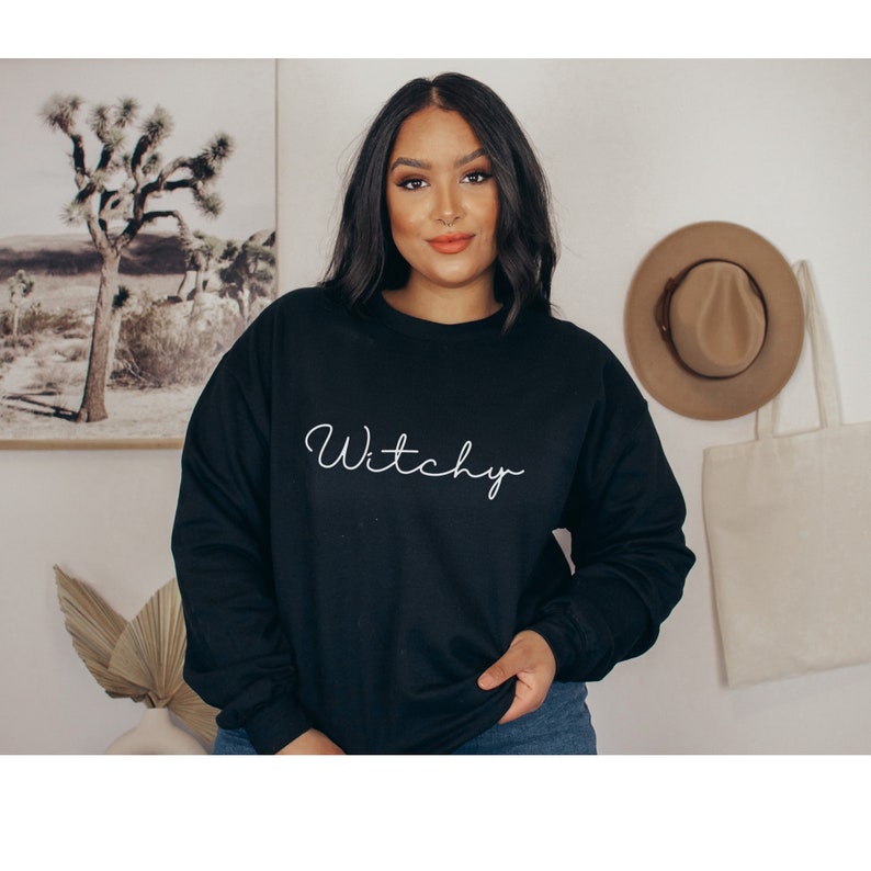 May include: Black sweatshirt with the word "Witchy" written in white cursive on the front.