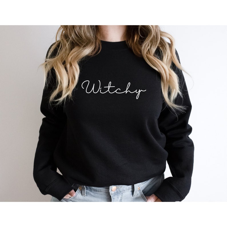 May include: Black sweatshirt with the word "Witchy" written in white cursive script.