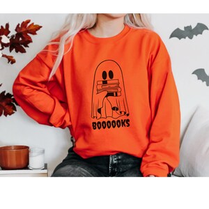 May include: Orange sweatshirt with a black ghost holding a stack of books and the text "BOOOOOKS".