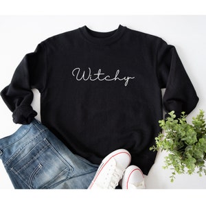 May include: Black sweatshirt with the word "Witchy" written in white cursive on the front.