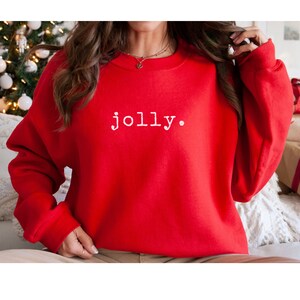 May include: Red Christmas sweatshirt with the word "jolly" printed in white.