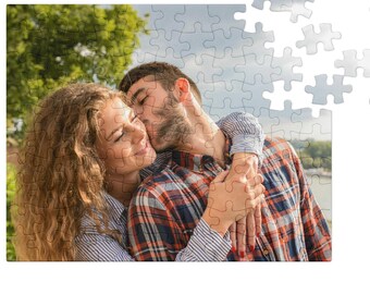 Può includere: Un puzzle con una coppia che si abbraccia e si bacia. L'immagine sul puzzle mostra un uomo che bacia una donna sulla guancia. I pezzi del puzzle sono per lo più assemblati, con alcuni pezzi separati.