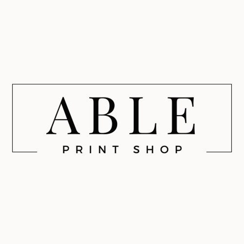 May include: Logo for Able Print Shop, featuring the word "ABLE" in a bold, serif font above "PRINT SHOP" in a smaller, sans-serif font, all within a rectangular frame. The text is black against a cream background.