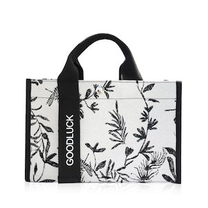 May include: A black and white tote bag with a floral pattern and the word "GOODLUCK" printed on the side.