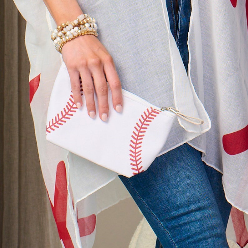 Puede incluir: Clutch blanco con tem&aacute;tica de b&eacute;isbol con detalles de costuras rojas. El clutch tiene un cierre de cremallera y un peque&ntilde;o lazo. El dise&ntilde;o imita el aspecto de una pelota de b&eacute;isbol.