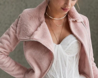 May include: A light pink faux fur jacket with a wide collar and a silver zipper closure, worn over a white strapless dress featuring a structured bodice and a layered tulle skirt. The jacket has long sleeves and a soft, textured finish.