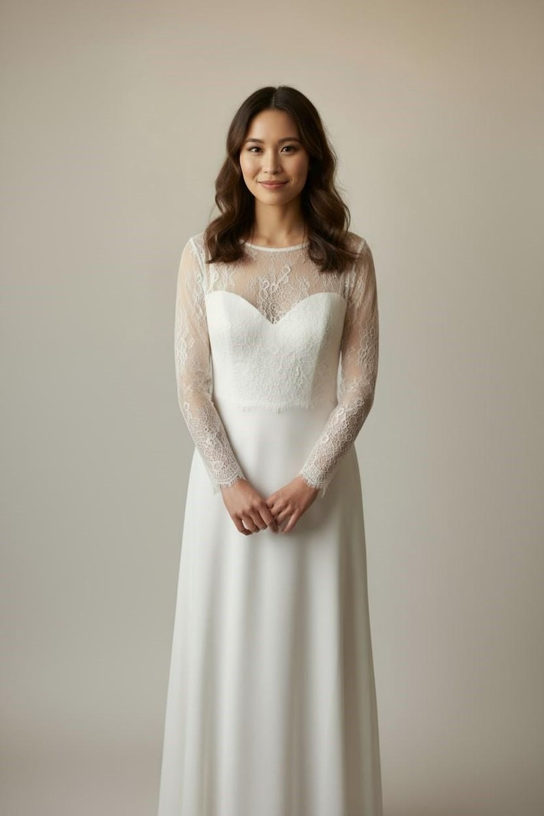 Bride wearing a white lace top with long sheer sleeves, styled as a wedding dress topper lace bolero shrug and floral lace blouse for wedding.