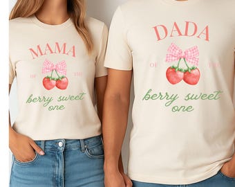 May include: Two cream-coloured t-shirts with matching designs. One shirt says "MAMA of the berry sweet one" and the other says "DADA of the berry sweet one". Each shirt features a watercolour illustration of cherries and a pink gingham bow.