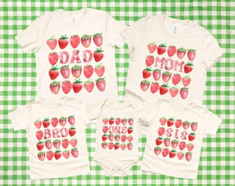 May include: Set of five white t-shirts with strawberry graphics and the words "DAD", "MOM", "BRO", "ONE", and "SIS" printed on them.