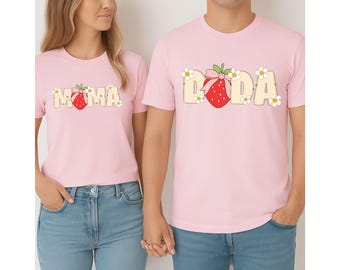 May include: Two pink t-shirts with a strawberry graphic and the words "MOMA" and "DODA" in white. The shirts are a matching set.