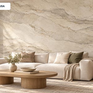 May include: A wall mural featuring a beige and cream marble stone pattern with grey veining. The mural is displayed behind a white sofa with beige and olive green throw pillows, a wooden coffee table, and a small side table with a lamp.