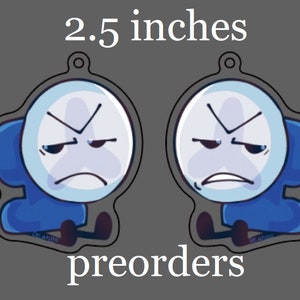 May include: Two cartoon character keychains, each 2.5 inches in height, featuring a white face with an angry expression and a blue body. The word "preorders" is written at the bottom. The keychains have a small hole at the top for attachment.