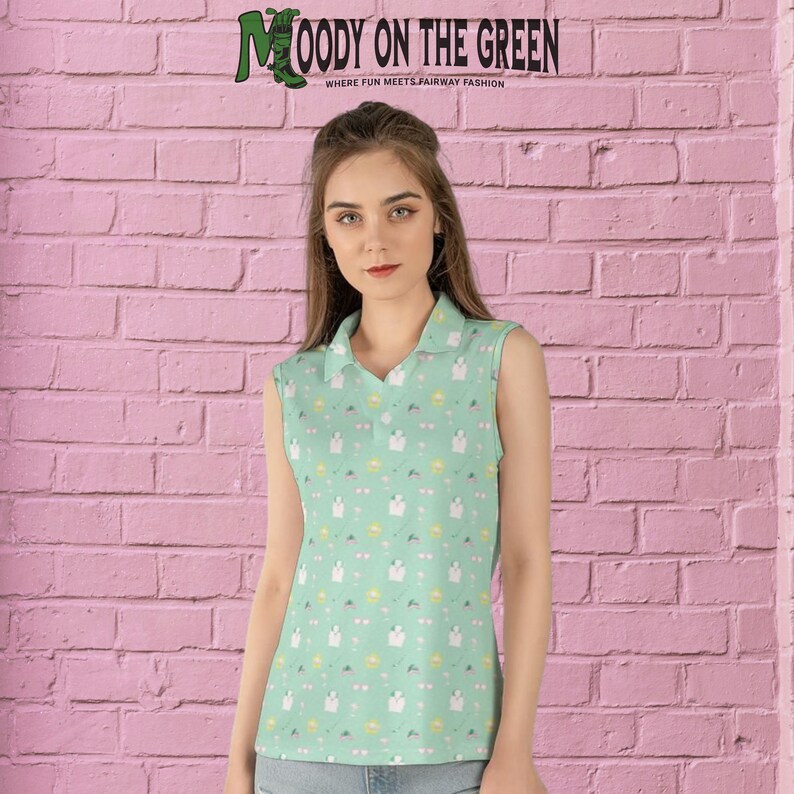 May include: A sleeveless green polo shirt with a white and yellow pattern. The shirt has a collared neckline and a button closure. The text "MOODY ON THE GREEN" is printed on the shirt. The text "WHERE FUN MEETS FAIRWAY FASHION" is printed below the main text.