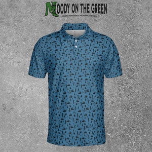 May include: A blue short-sleeved polo shirt with a black pattern of golf-related icons. The shirt has a collar and a button placket. The text "MOODY ON THE GREEN" is printed on the shirt in green letters. The text "WHERE FUN MEETS FAIRWAY FASHION" is printed below the main text in smaller letters.
